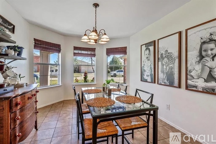 A dining room with a table set for four and a chandelier hanging from the ceiling.