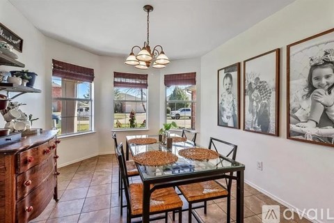 A dining room with a table set for four and a chandelier hanging from the ceiling.
