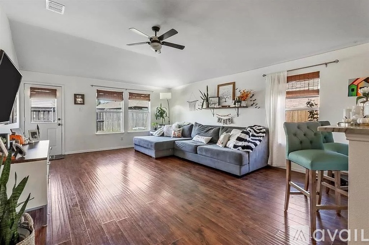 A living room with a grey couch and a ceiling fan.