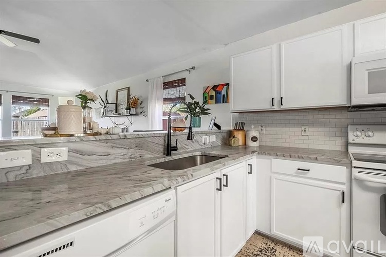 A kitchen with white cabinets and a marble countertop.