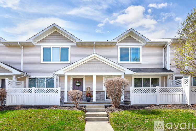 A two-story house with a front porch and white fence.
