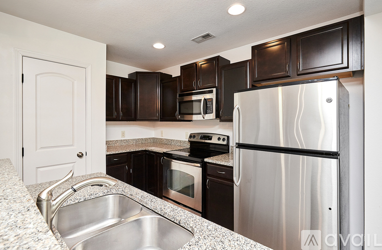 A kitchen with a stainless steel refrigerator and a granite countertop.