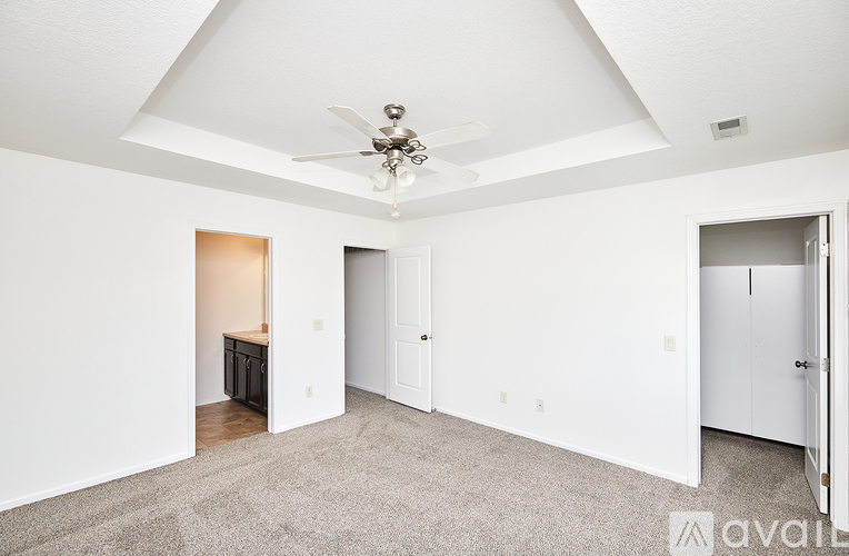 A spacious room with a ceiling fan and carpeted floor.