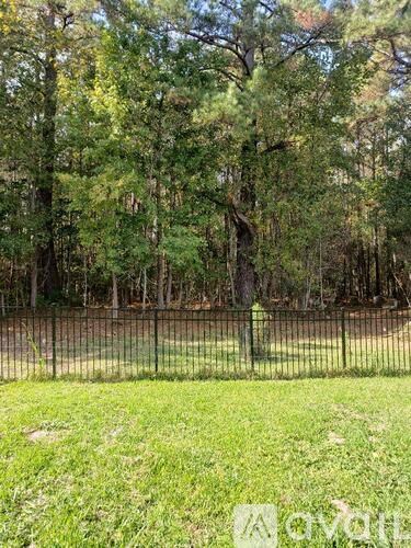 A fenced area with a grassy field and trees in the background.