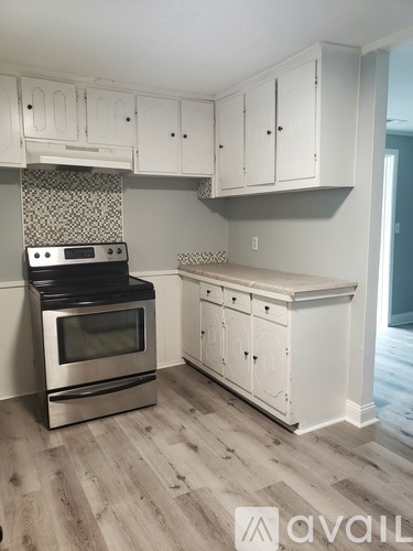 A kitchen with white cabinets and a stove top oven.