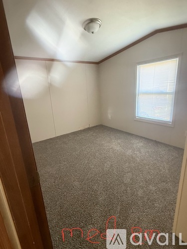 A room with a carpeted floor and a window with blinds.