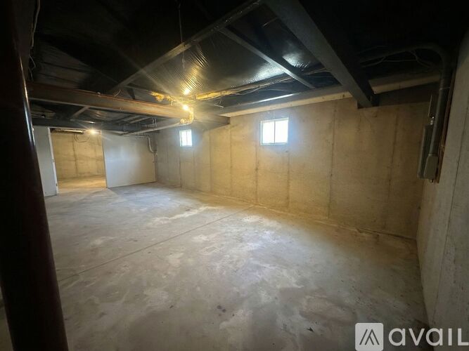 A spacious attic room with exposed beams and two windows.