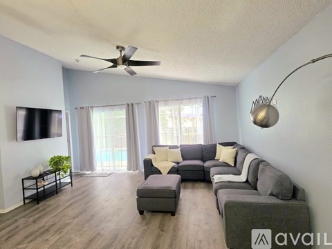 A living room with a grey couch and a flat screen TV mounted on the wall.