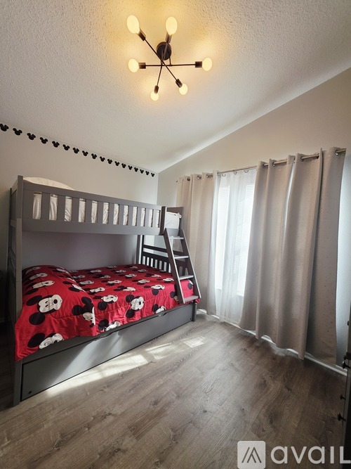 A bedroom with a bunk bed and a window with curtains.
