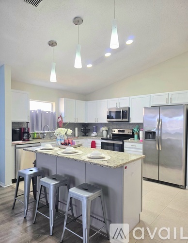 A kitchen with a bar stool and a fridge.