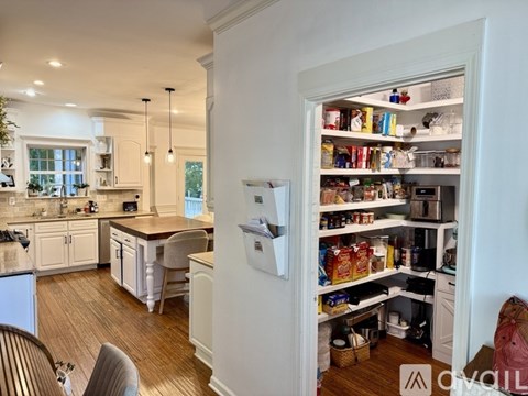 A kitchen with a refrigerator full of food and a dining table with chairs.