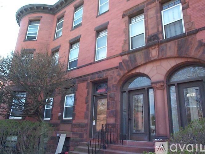 A red brick building with a black iron fence in front.