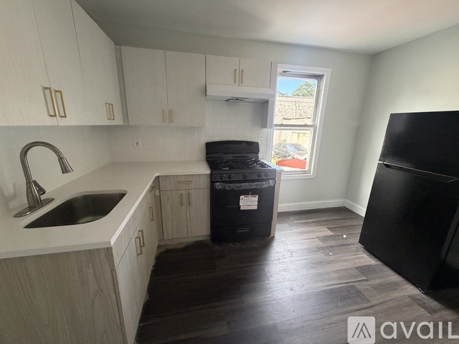 A kitchen with a black fridge and a black trash bin.