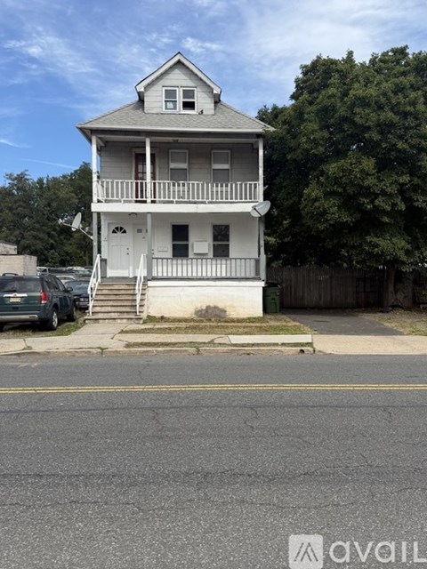 A two-story house with a white exterior and a balcony on the second floor.
