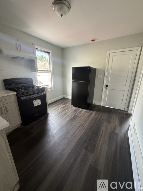 A kitchen with a black fridge and a black stove top.
