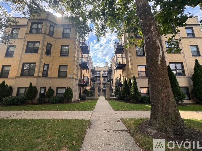 A tree stands in front of a building with a balcony.