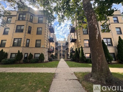A tree stands in front of a building with a balcony.