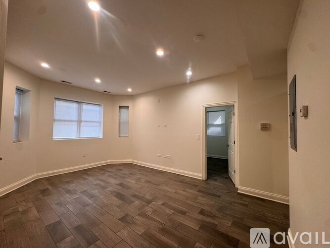 A spacious room with wooden flooring and a doorway leading to another room.