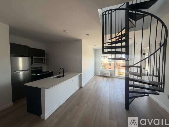 A modern kitchen with a spiral staircase in the background.