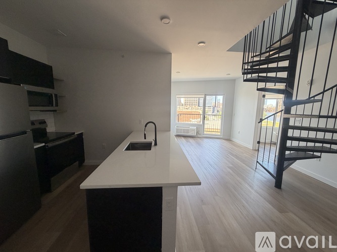 A kitchen with a white countertop and a black staircase.
