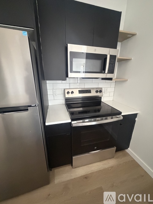 A kitchen with a stainless steel refrigerator and a black oven.