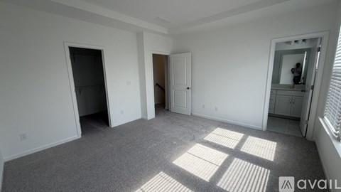 A spacious room with a carpeted floor and a large window letting in natural light.