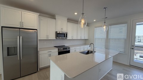 A kitchen with a refrigerator, microwave, and a countertop with a sink.