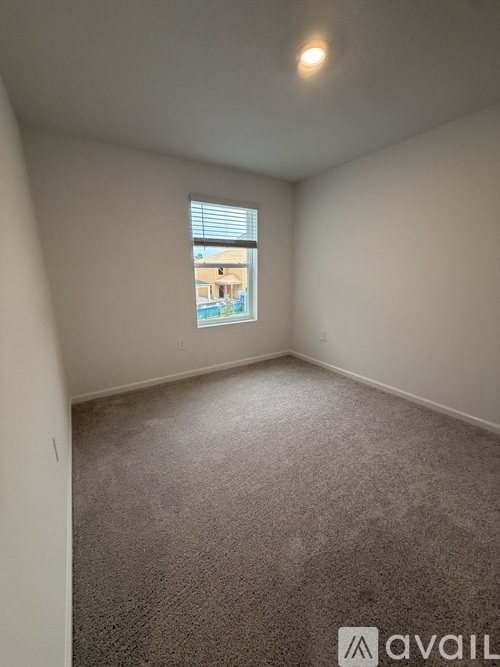 A room with a carpeted floor and a window showing a building outside.