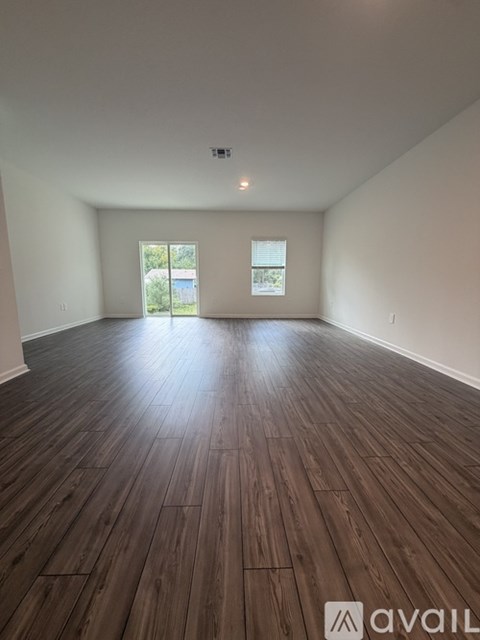 A spacious room with wooden flooring and a window.