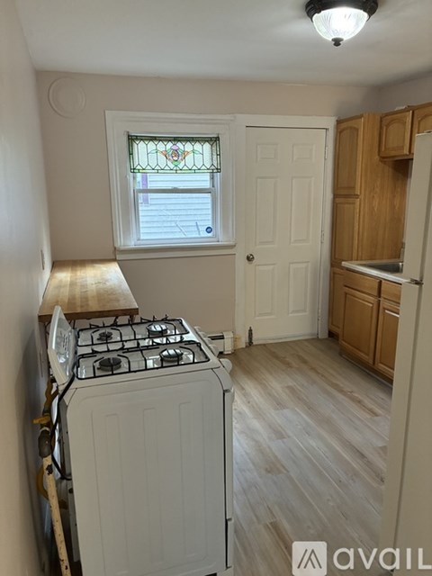 A small kitchen with a stove and wooden cabinets.