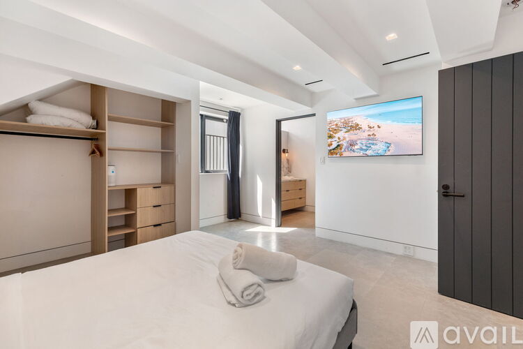 A bedroom with a large bed and a flat screen TV mounted on the wall.