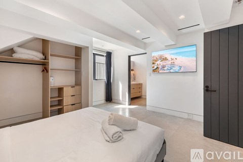 A bedroom with a large bed and a flat screen TV mounted on the wall.