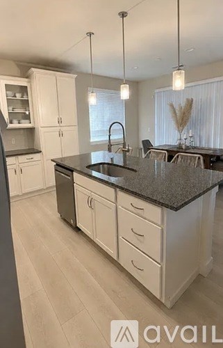 A modern kitchen with a granite countertop and white cabinets.