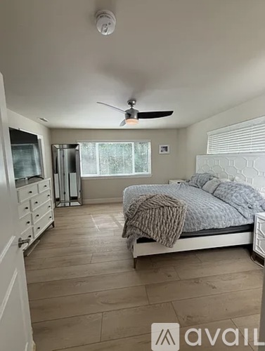 A bedroom with a bed, dresser, and ceiling fan.