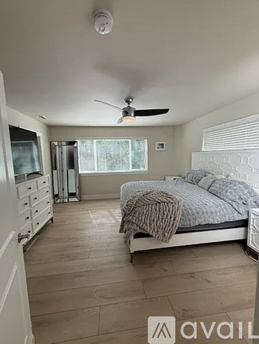 A bedroom with a bed, dresser, and ceiling fan.