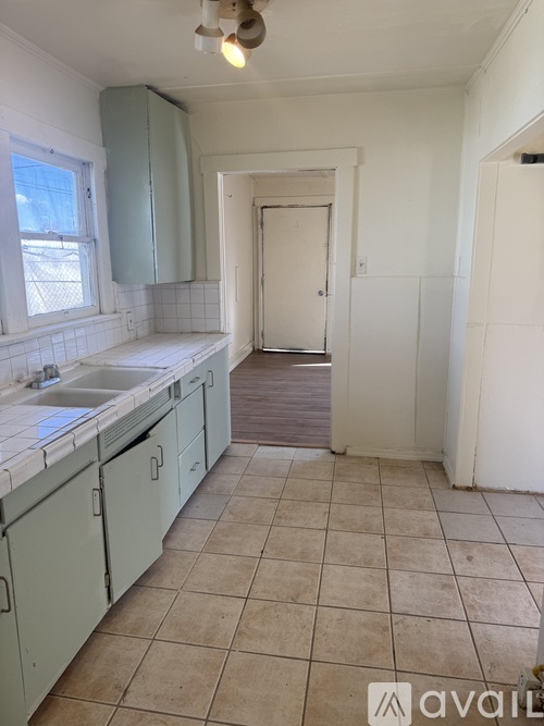 A kitchen with white cabinets and a tiled floor.