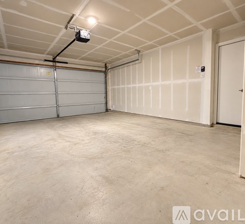 A spacious garage with a closed white door and a white wall with a vent.