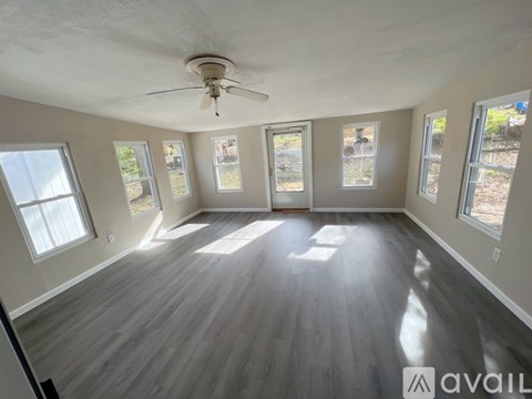 A spacious room with a ceiling fan and large windows.