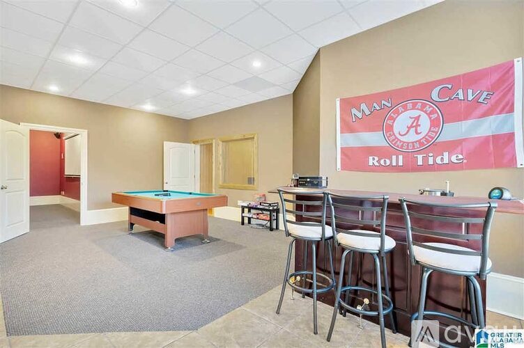A room with a pool table and bar stools.