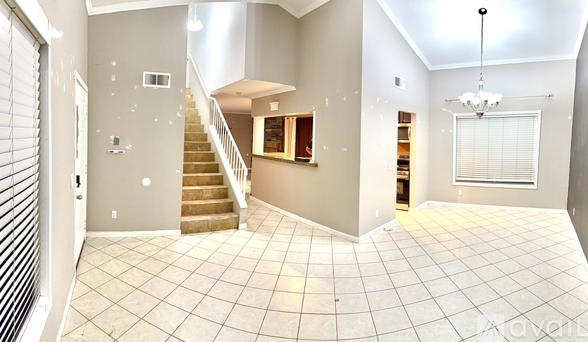 A spacious living room with a staircase leading to the upper floor.