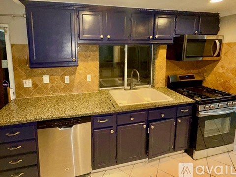 A kitchen with dark blue cabinets and granite countertops.