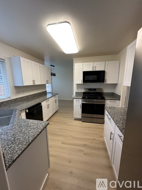 A kitchen with white cabinets and a granite countertop.