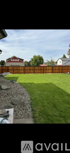 A backyard with a wooden fence and a grassy area.