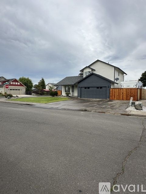 A house with a garage is situated on a street with a cloudy sky overhead.