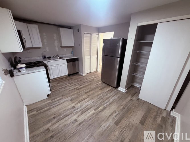 A kitchen with white appliances and wooden floors.