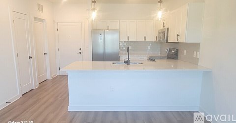 A kitchen with white cabinets and a white island.