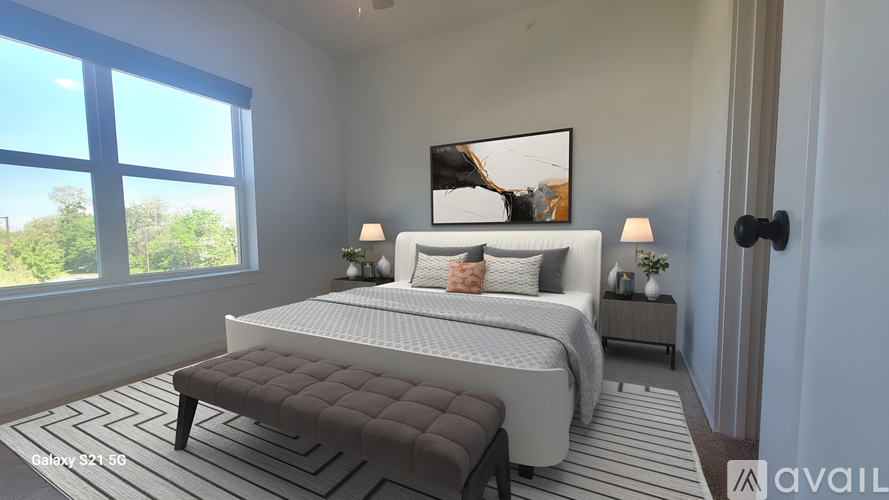 A bedroom with a large bed and a window overlooking a green landscape.