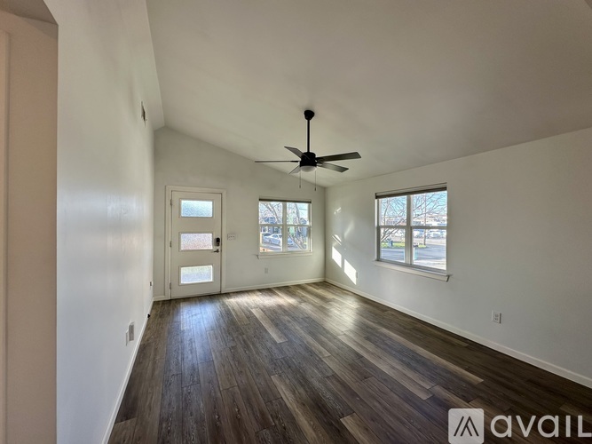 A room with a ceiling fan and wooden flooring.