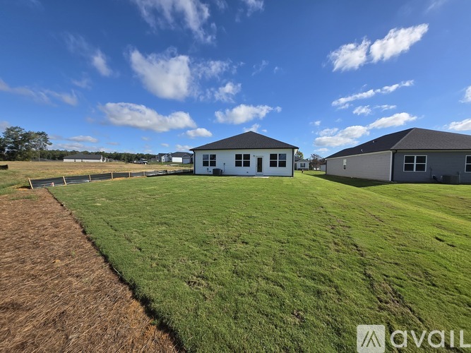 A grassy field with two houses and a clear sky.
