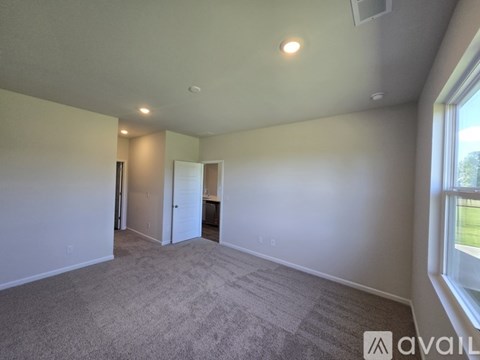 A spacious room with carpeted floor and two doors leading to other rooms.